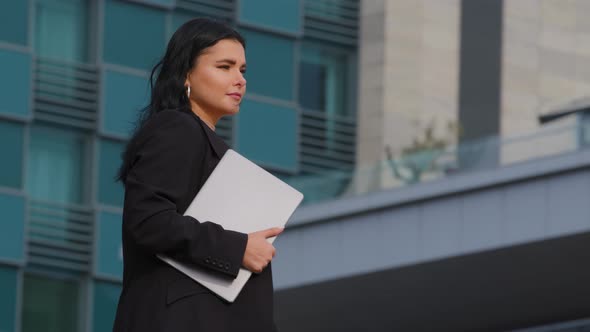 Young Serious Tired Pensive Businesswoman in Business Suit Walks Down Street Against Backdrop Office