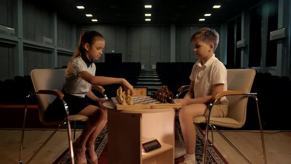 School-age children sit at the table and play chess. Cinematic