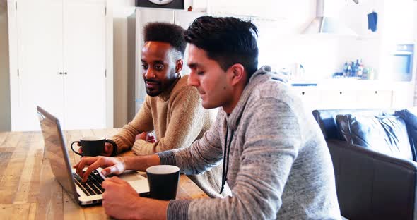 Gay couple using laptop while having coffee