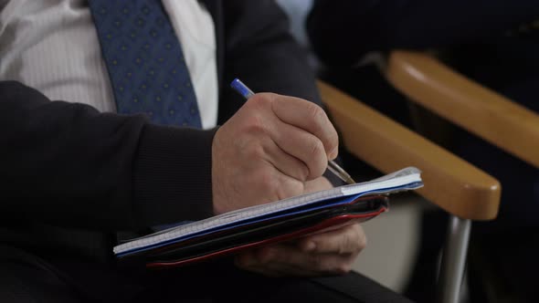 Closeup Man's Hands Writing Information at Seminar