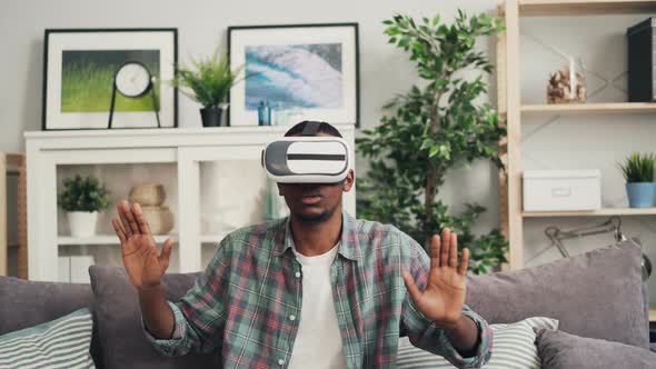 Zoom-in of African American Young Man Wearing Augmented Reality Glasses and Moving Hands Smiling and