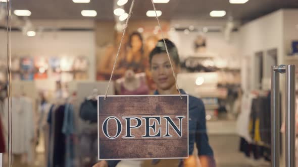 Young African American Woman Turning a Sign From Open to Closed on the Door of a Women's Brand