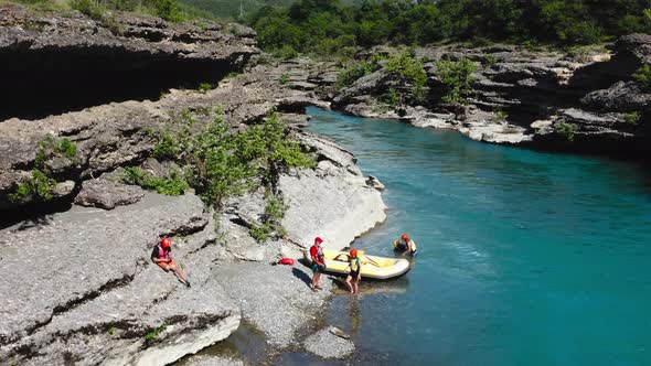 tourists disembark from inflatable boat at the Vjosa river edge after rafting, in Albania. Aerial or