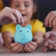 Closeup of Hand Throwing Coins Into Piggy Bank - VideoHive Item for Sale