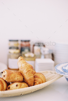 A table with a dish of croissants and pains au chocolat.