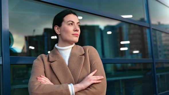 Cute Fashion Woman in Coat Posing Near Modern Glass Building