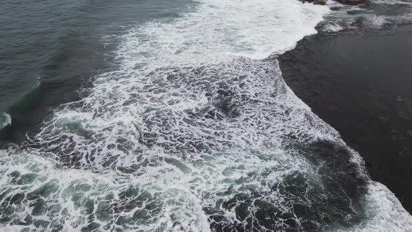 Aerial view of tropical beach in Gunung kidul, Indonesia with green and rocky cliff.