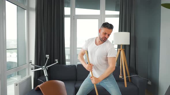 Man Cleaning the House and Having Fun Dancing and Singing with a Broom