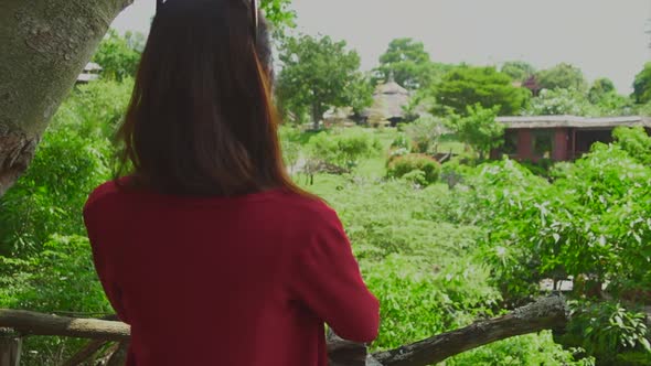 Asian Girl in red jacket taking picture by phone from the Tree house viewpoint