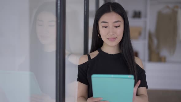 Portrait of Smiling Satisfied Young Asian Woman Checking Email on Tablet in the Morning in Home