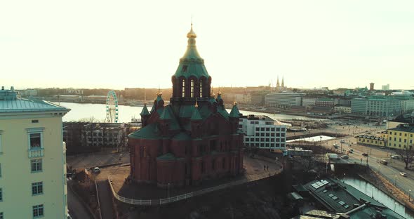 Aerial shot of a church in Helsinki during sunset. Slow orbit revealing sun behind.