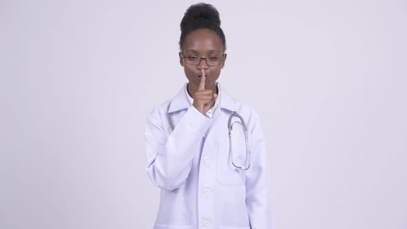 Young African Woman Doctor with Finger on Lips