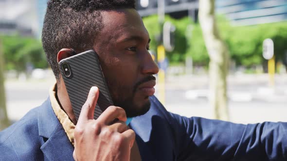 African american businessman talking on smartphone in city street