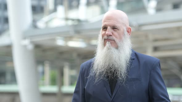 Face of Mature Bearded Bald Businessman with Sunglasses Thinking in the City Outdoors