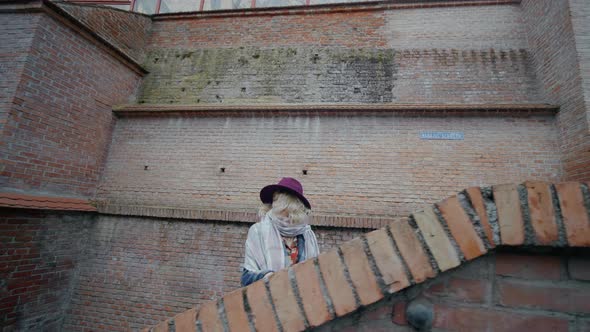 Tourist woman climbing on stone stairs watch steps while going upstairs.