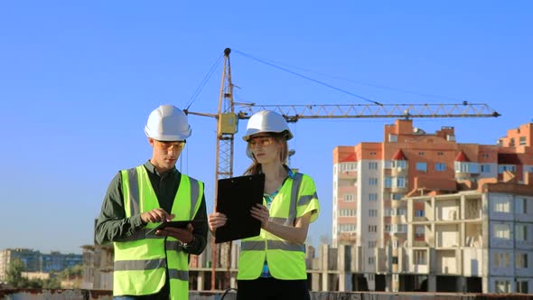 Young engineers architects guy and girl in protective helmet and vest about the project 