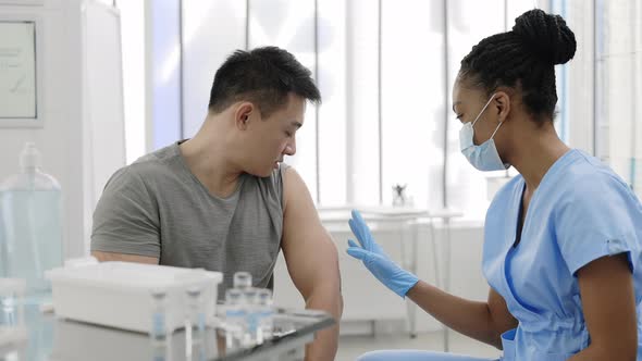 Crop View of Female Doctor Checking Patient Shoulder Before or After Vaccination and Communicating