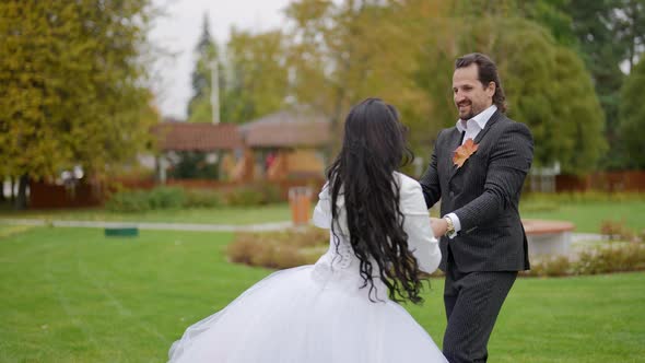 Happy Groom and Bride are Celebrating Their Wedding Dancing Together in Garden in Autumn Day