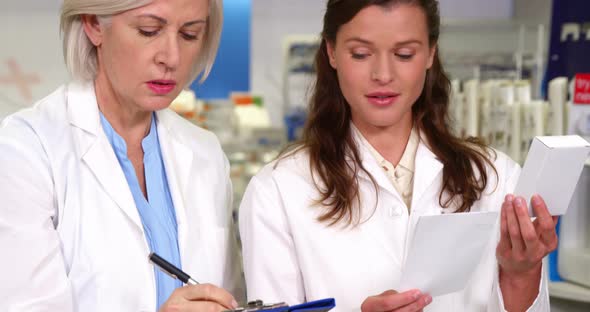 Pharmacists maintaining a record of medicine on clipboard