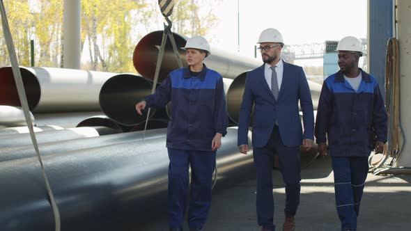  Plant Workers Showing Steel Pipes to Male Supervisor