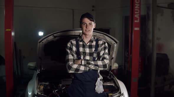 Portrait of Young Handsome Car Mechanic in Workshop in the Background of Service