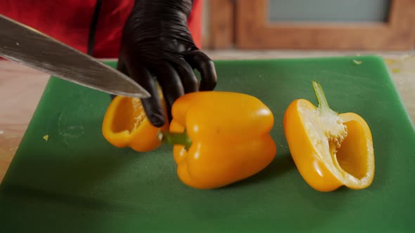 Close Up Cook Hands in Black Gloves Cut Yellow Bell Pepper with Knife
