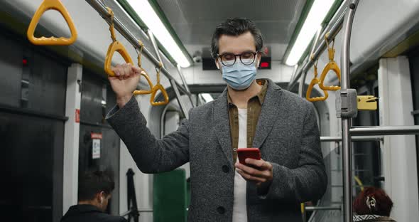 Crop View of Handsome Guy in Medical Mask and Glasses Using Smartphone