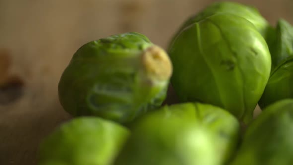Close up of a bunch of fresh, green brussel sprouts resting on a wood cutting board