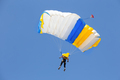 Skydiver under canopy of yellow with blue parachute in cloudless sky - PhotoDune Item for Sale