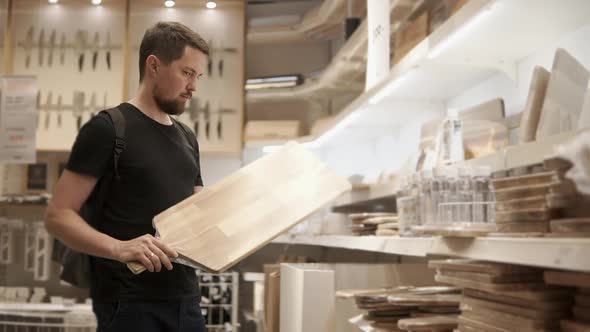 Buyer is Looking and Holding Big Cutting Board in Mall with Tableware Department