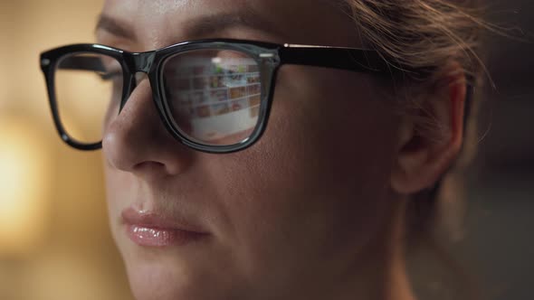 Woman in Glasses Looking on the Monitor and Surfing Internet. The Monitor Screen Is Reflected in the