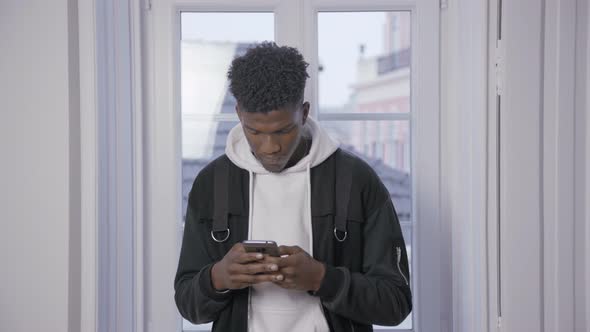 Serious African American Student Texting Message on Smartphone