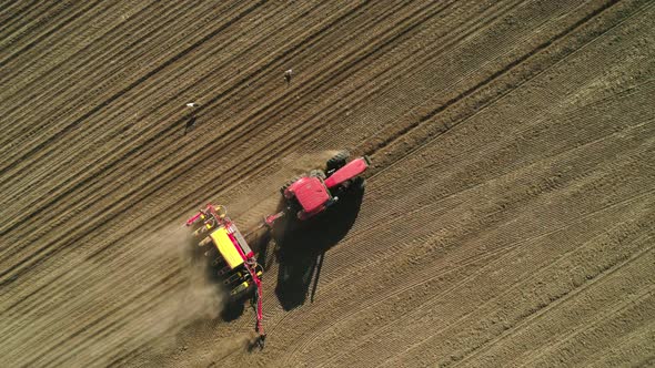 Aerial Top Down View of Tractor Working in the Field with a Modern Sowing Seeds Machine in a Newly