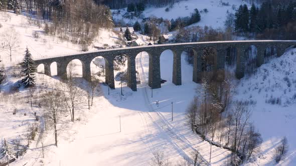 Aerial view of a stone railway viaduct and a small village,winter snow.