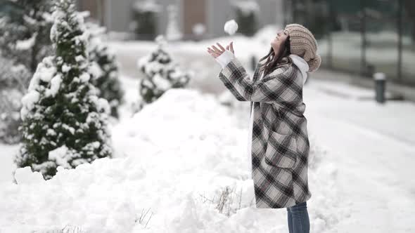 Joyful Lady Is Playing with Snowball at Winter Street Cold Day in City Happy Vacation at Christmas