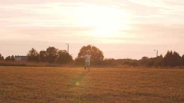 Little boy plays with a toy plane in a field at sunset. Childhood, freedom, inspiration concept.