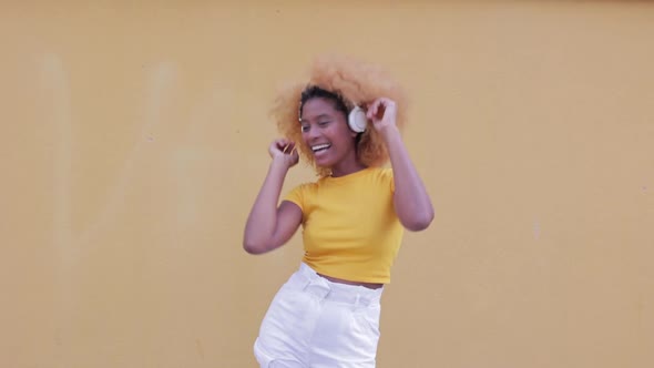 Cheerful Positive African American Woman Dancing in Front of Yellow Wall