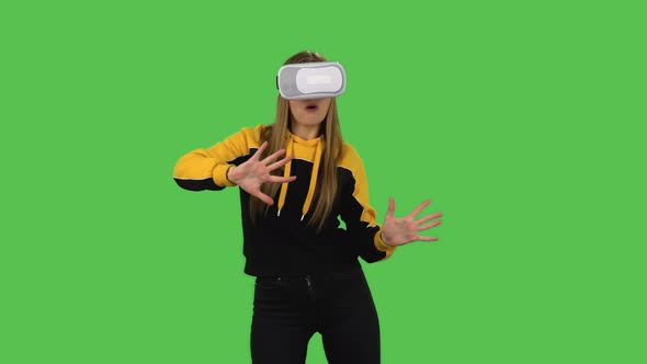 Modern Girl in Yellow Hoodie with Virtual Reality Headset or 3d Glasses. Green Screen