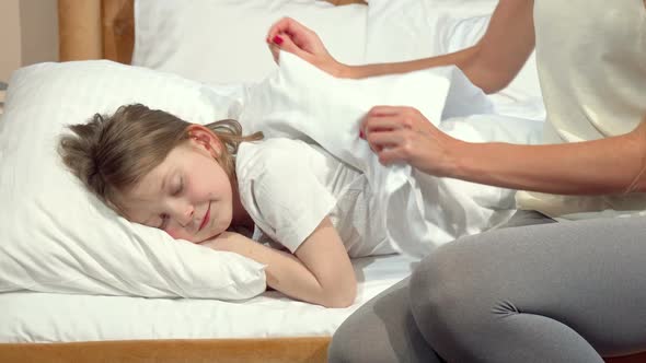 Unrecognizable Woman Tucking the Blanket for Her Little Sleeping Daughter