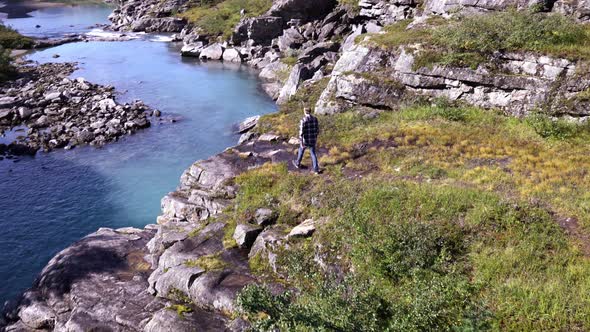 Man walking towards river in beautiful nature scenery, 4K, Norway, Europe.