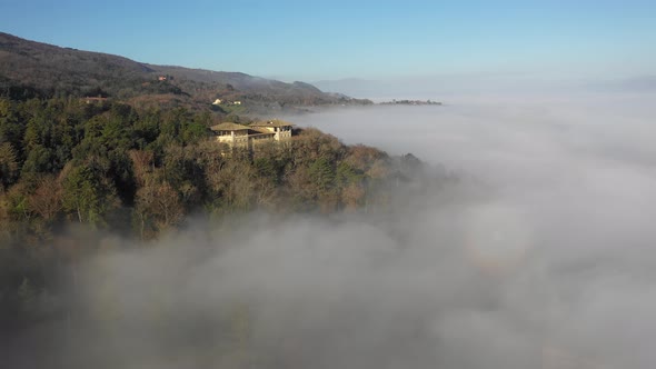 Aerial view of a palace with fog in the forest in Umbria, Italy