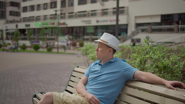A Tourist Sits on a City Bench Rests While Walking Around the City