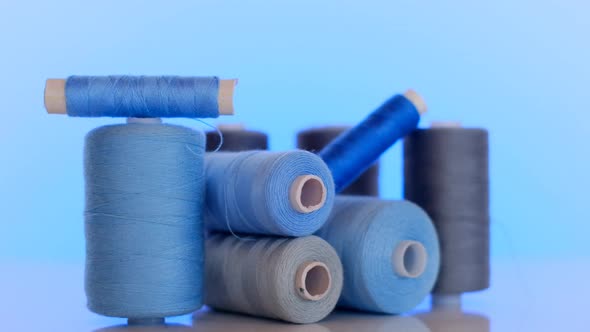 Sewing threads.Blue and gray thread spools on a light blue background.