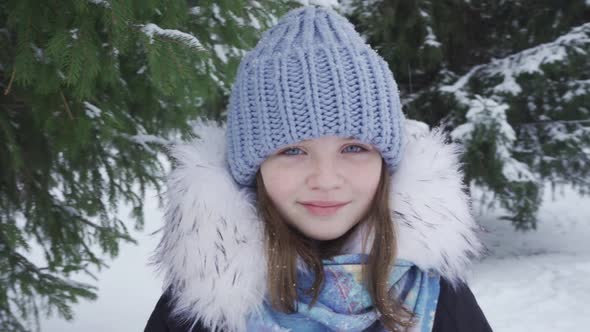 Portrait of a Happy Blueeyed Teenage Girl in a Snowy Park