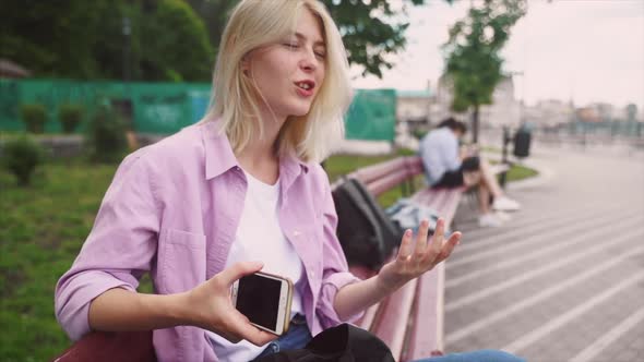 Teen Girl Using a Smart Phone and Texting Sitting in a Bench