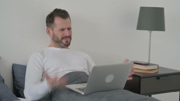 Man Reacting to Loss on Laptop in Bed