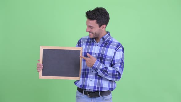 Happy Young Hispanic Man Holding Blackboard and Giving Thumbs Up