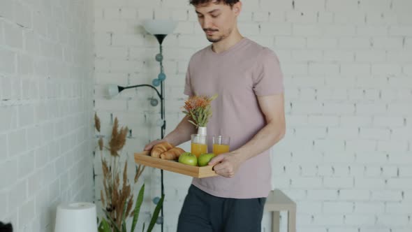 Handsome Man Bringing Breakfast to Bed Expressing Love to Beautiful Asian Woman Kissing Indoors at