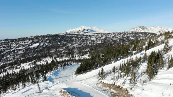 Snowy Mountain Hill with Ski Lift and Forest Under Blue Sky