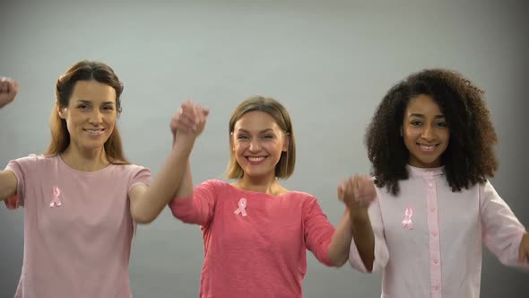 Smiling Women With Pink Ribbon Raising Hands Up, Fighting Against Breast Cancer